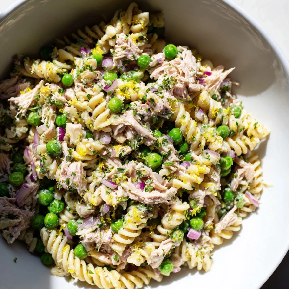 Bright Lemony Tuna Pasta Salad with flaked tuna, sweet peas, and fresh herbs served chilled on a picnic blanket.  