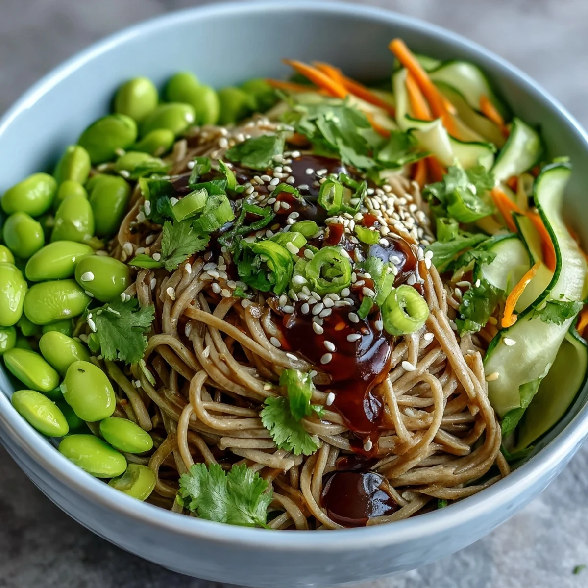 A close-up of a vibrant Soba Noodle Bowl featuring chewy buckwheat noodles, edamame, and crisp vegetables drizzled with sesame dressing.