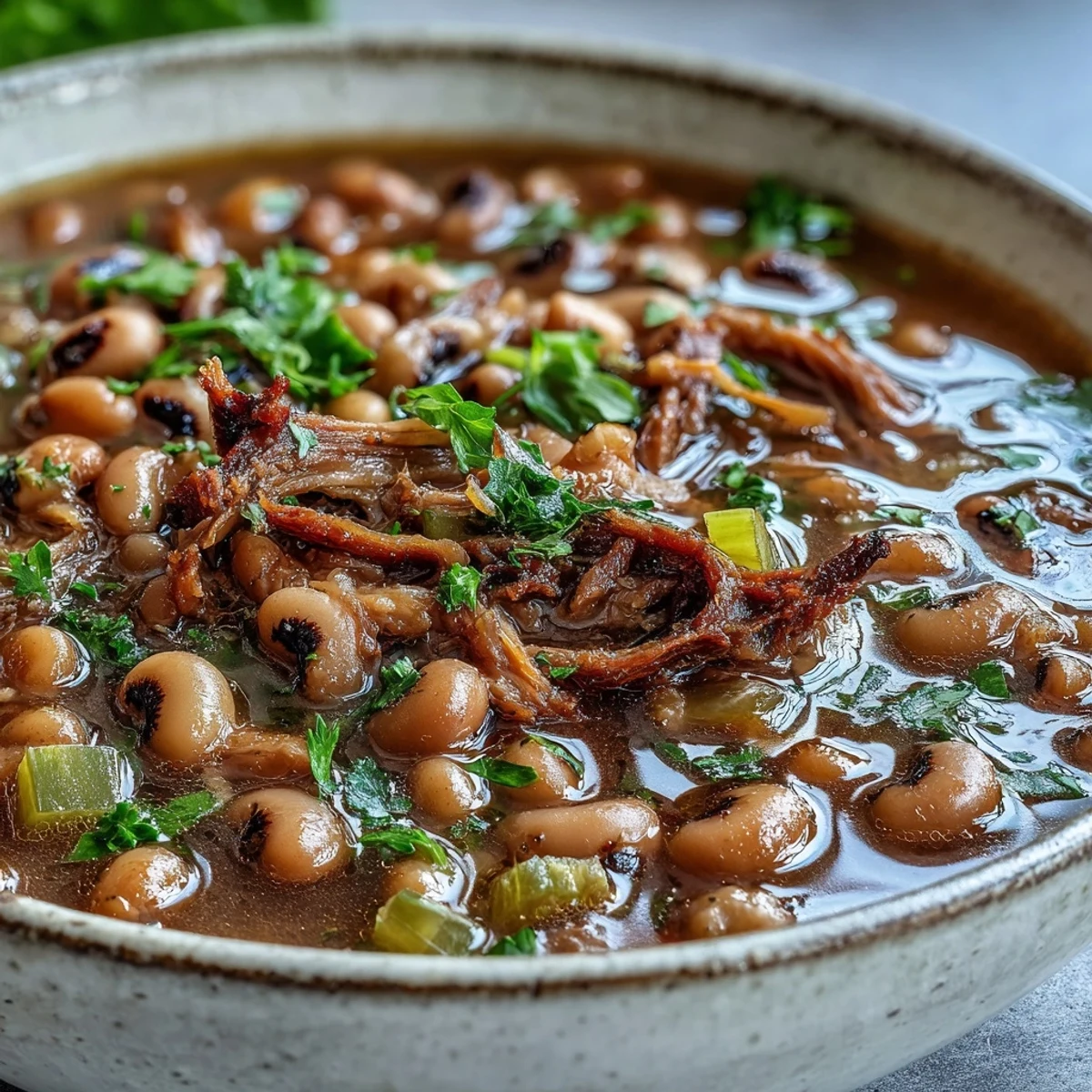 A bowl of hearty Classic New Years Black-Eyed Peas garnished with fresh parsley, showcasing the rich, savory broth and tender pork.