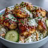 A colorful bowl of Bang Bang Chicken Bowl garnished with green onions and sesame seeds, drizzled with extra spicy sauce over crunchy red cabbage.