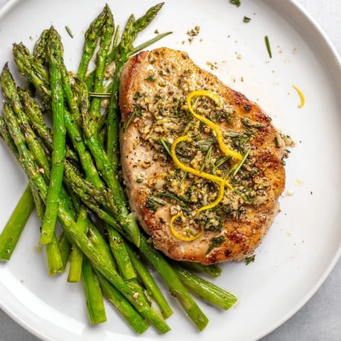 Golden brown one-pan lemon herb pork chops with asparagus, ready for a flavorful, easy dinner.