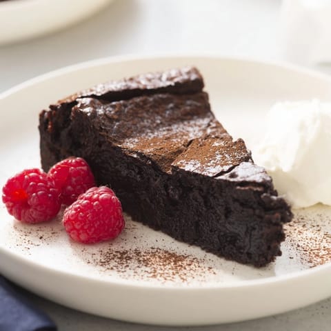This rich, fudgy decadent flourless chocolate cake is ready to serve with a swirl of whipped cream.