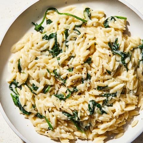 Visualize the rich, creamy texture of Creamy Spinach Orzo, bubbling in a skillet with spinach.
