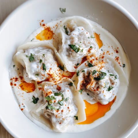 Steaming plate of Turkish cheesy manti, with delicate, cheese-filled dumplings and a rich yogurt sauce.