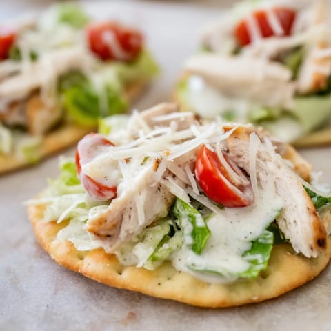 Freshly grated Parmesan and cherry tomatoes garnish the Caesar Chicken Flatbread, served with lemon wedges and extra dressing.