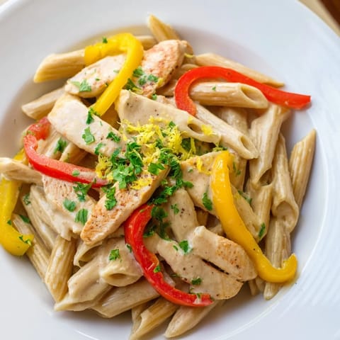 Steaming bowl of Creamy Cajun Chicken Pasta Lite garnished with parsley, paired with a crisp green salad for dinner.