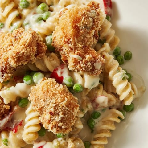 A hearty serving of Crispy Chicken Ranch Pasta Salad showcases tender rotini, sweet peas, and crunchy panko-coated chicken.