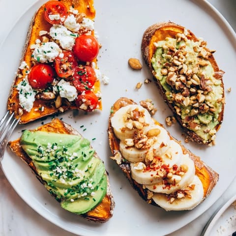 Golden roasted sweet potato toast slices topped with creamy avocado and vibrant cherry tomatoes, ready to eat.