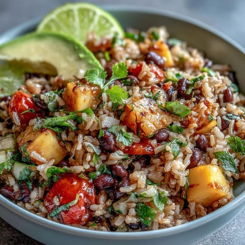 A colorful bowl of mango and black bean brown rice topped with fresh veggies and zesty lime dressing.  