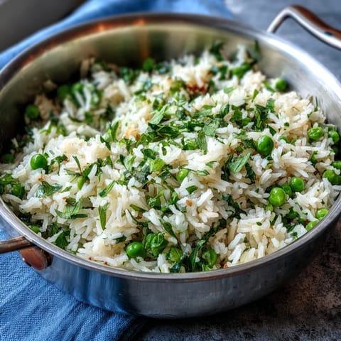 A vibrant bowl of Spring Pea and Mint Rice Pilaf, featuring bright green peas and fresh mint scattered over fluffy rice.