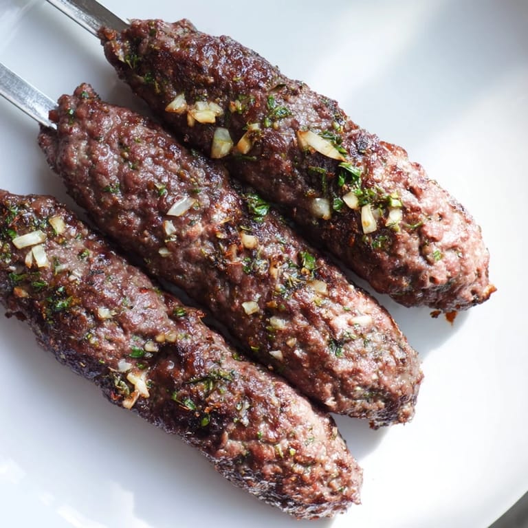 Savory Iraqi Kebab Tikka, cooked over open flames, glistening and served atop warm flatbreads with fresh accompaniments.