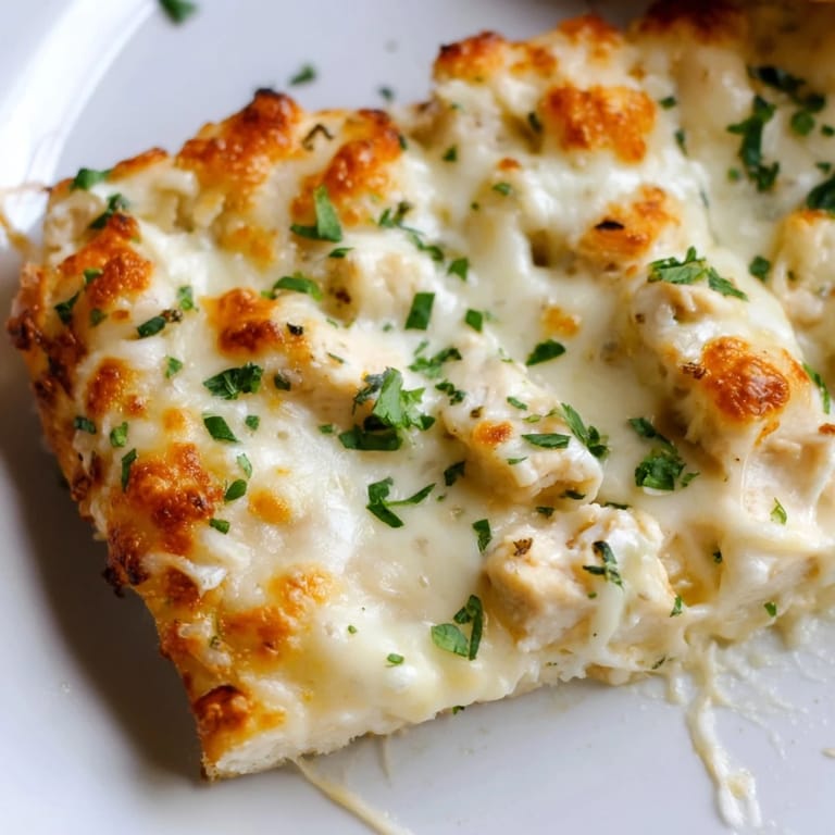 Overhead view of Chicken Alfredo Pizza garnished with fresh parsley, ready to serve with a side salad for a delicious, family-friendly main dish.