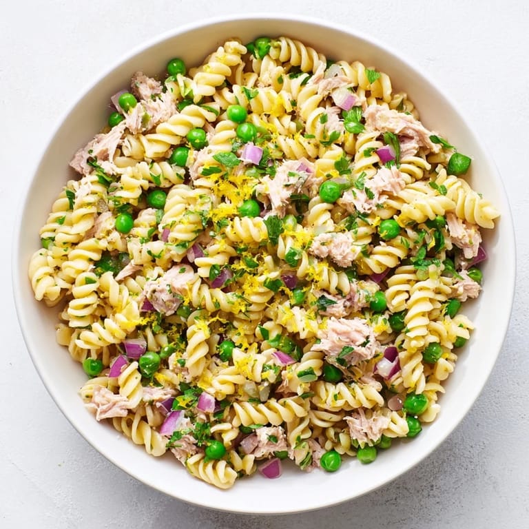 Freshly plated Lemony Tuna Pasta Salad garnished with parsley and cherry tomatoes, ready for a light lunch or potluck.