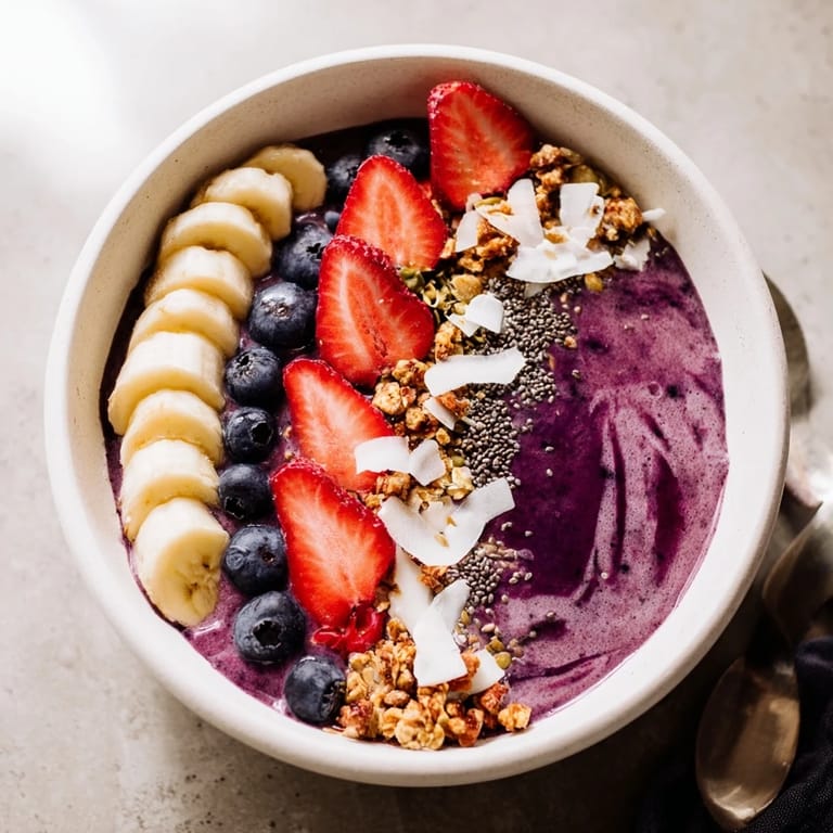 Vibrant Acai Berry Smoothie Bowl topped with strawberries, blueberries, and chia seeds, ready to enjoy with a spoon.  