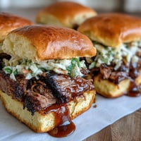 Smoky BBQ brisket piled high on soft slider buns, topped with tangy slaw and drizzled with rich barbecue sauce.